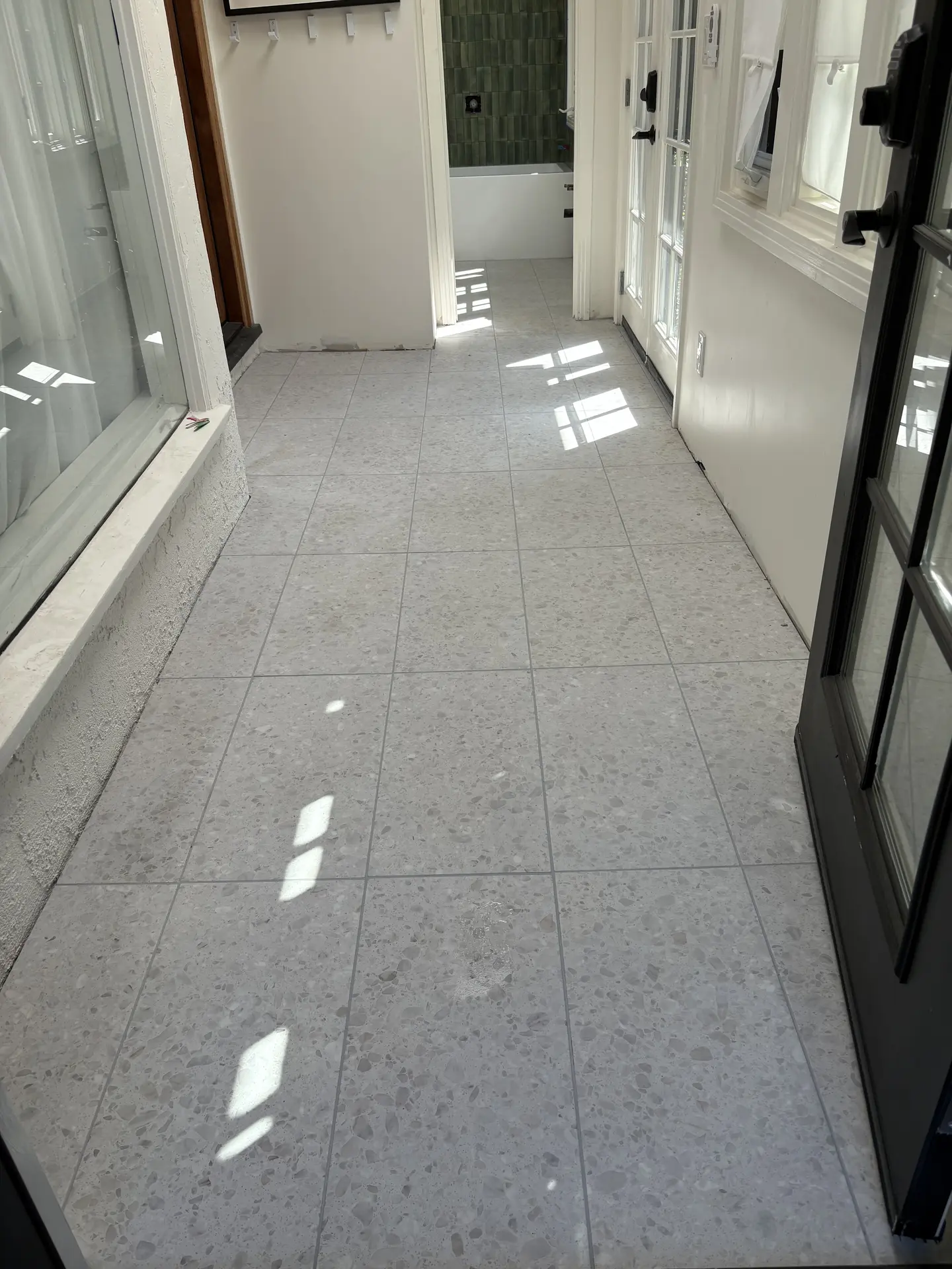 Coordinated tile floor leading into a green tile bath by C-TILE Custom Work