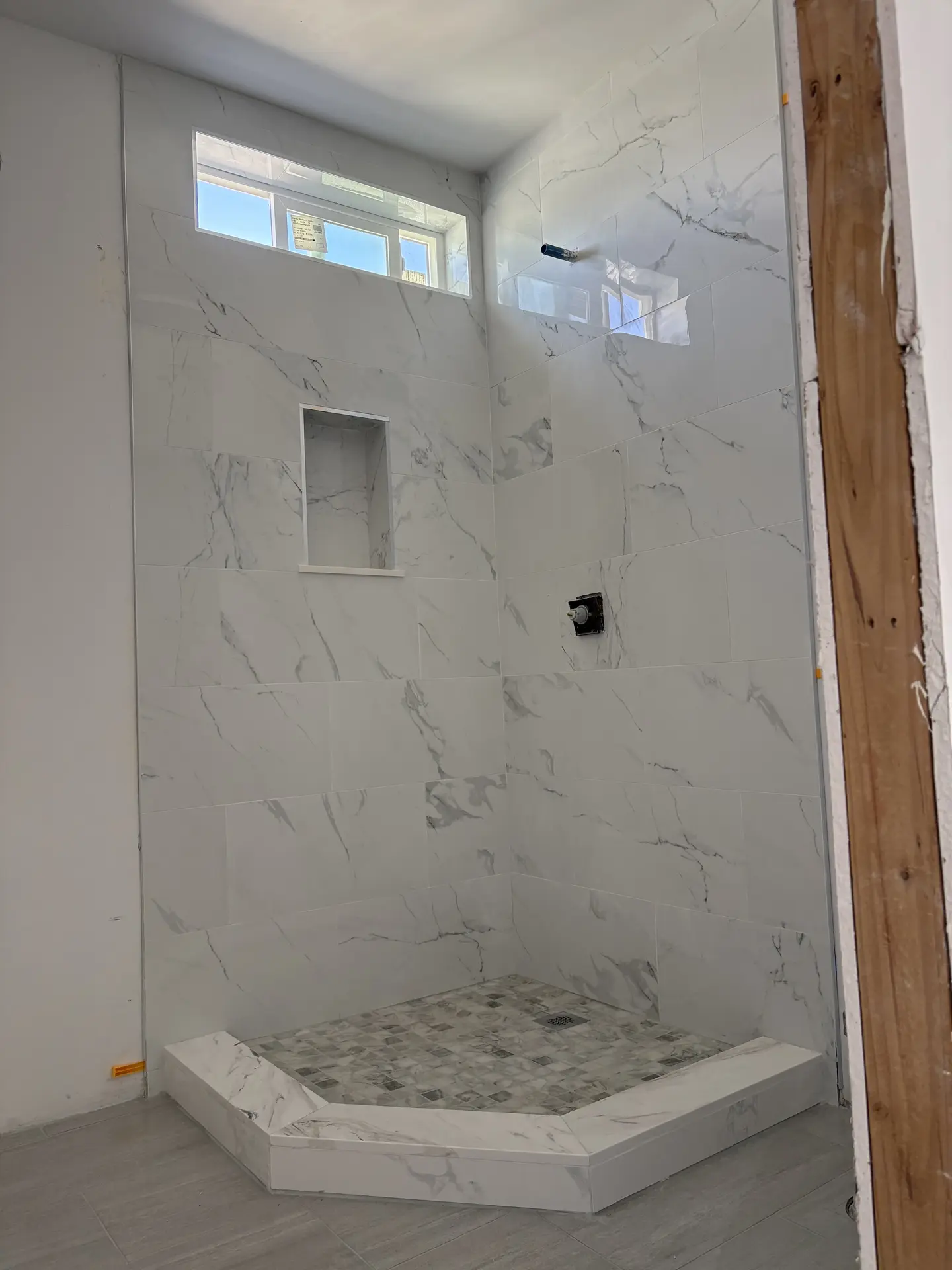 Light stone-look shower wall and recessed niche installed by C-TILE Custom Work
