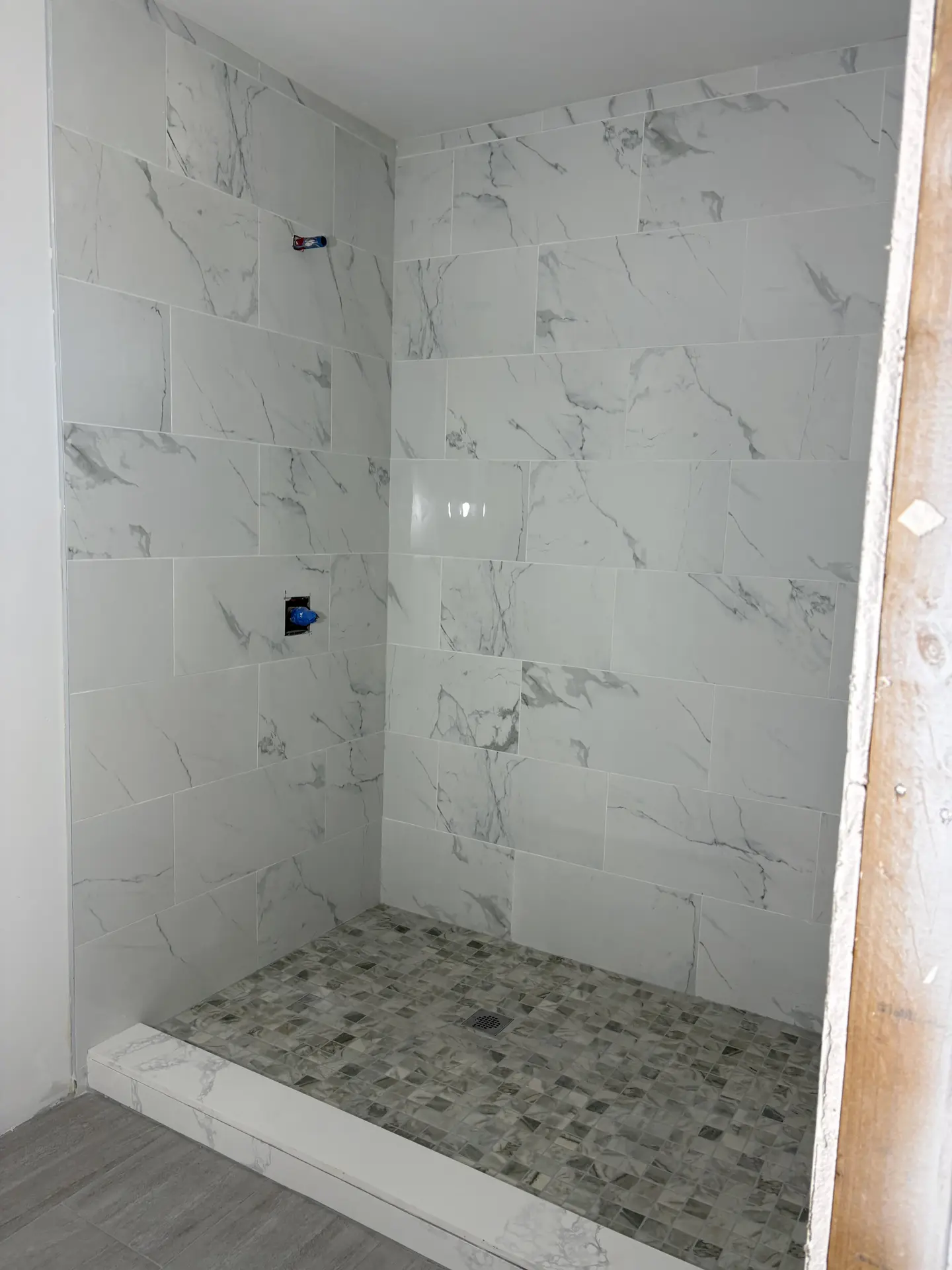 Light stone-look shower with mosaic floor installed by C-TILE Custom Work
