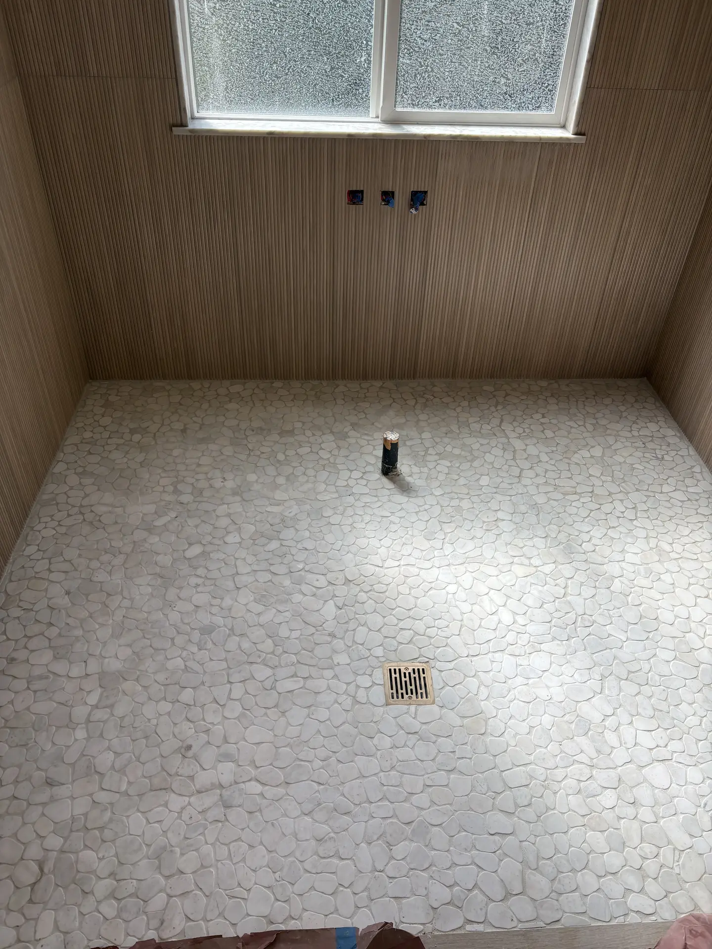 Pebble-style shower floor and linear wall tile detail by C-TILE Custom Work